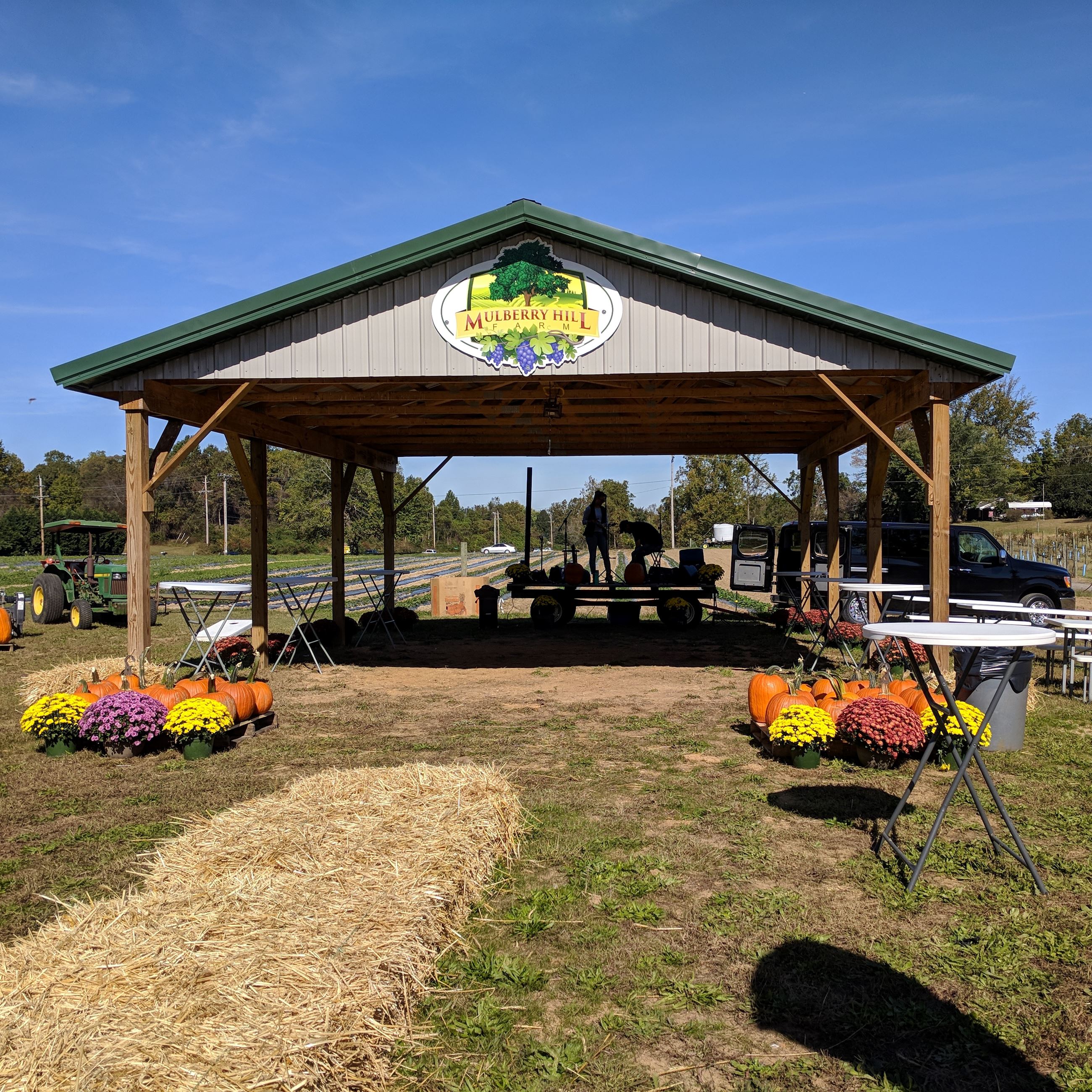 Pavilion with mums and pumpkins with tractor in the background