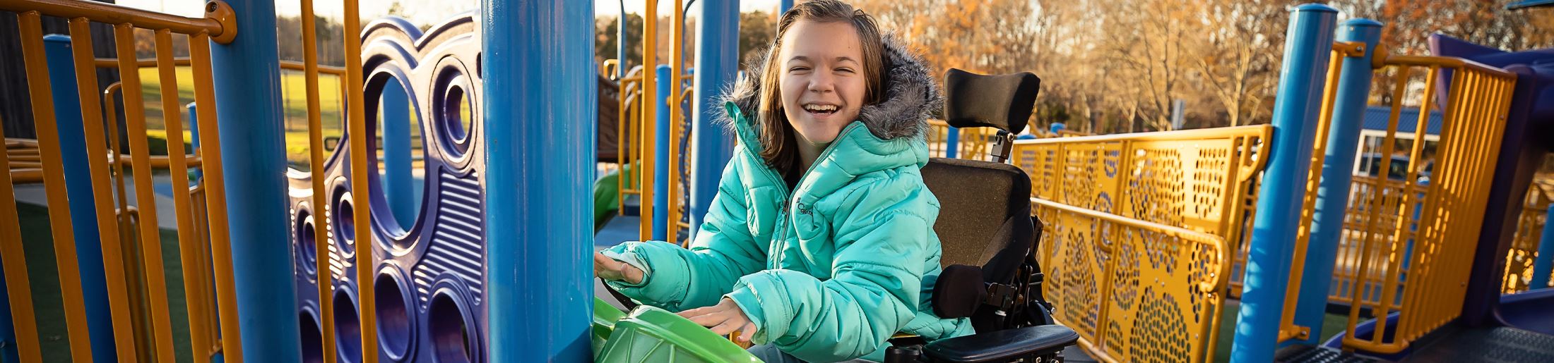 A girl in a wheelchair playing drums on a playground
