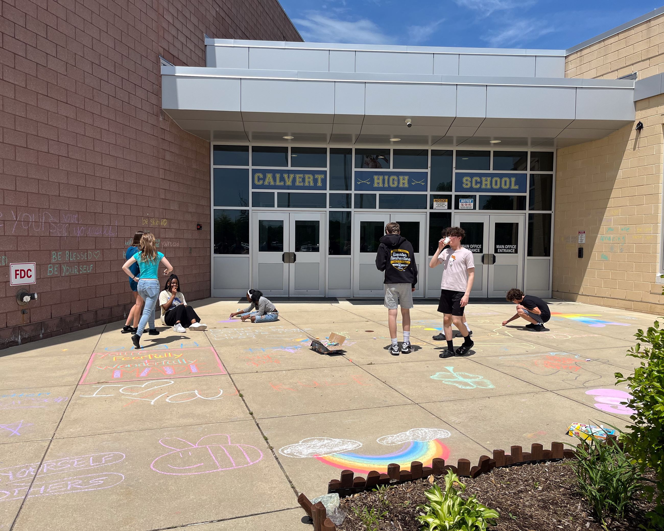 Sidewalk chalk art of strawberries next to a sun, clouds and a flower.
