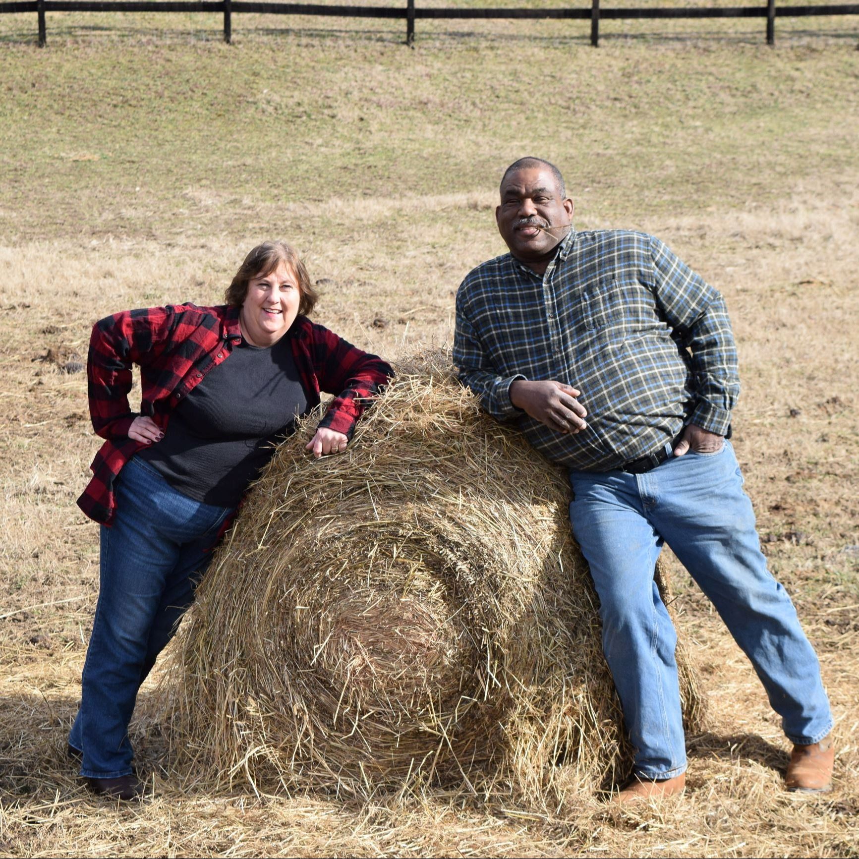 Man and woman standing by a hay bale